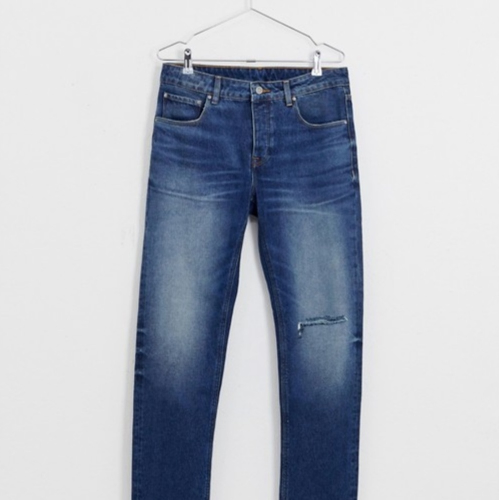 slim jeans in dark wash blue with busted knee rip